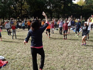 ３ヵ月ぶりに開催された代々木公園練習会の体操風景です。エアロビのＷさんの指導後ろ姿が大きく写っていて、体操する皆さんが５０人ほど写っています。
